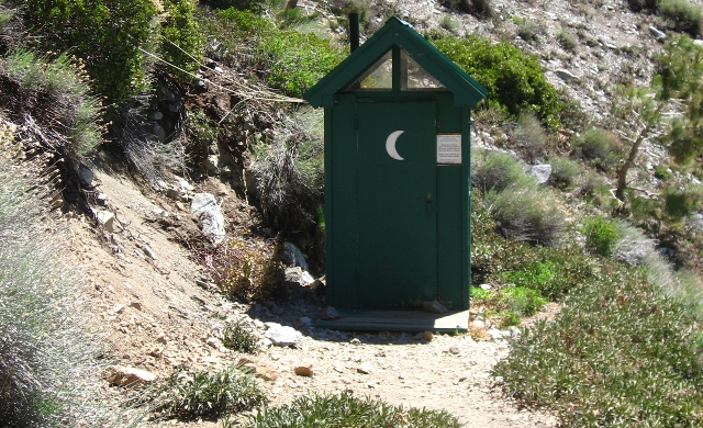 A green outhouse just off the trail.